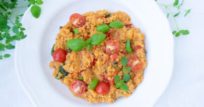 Baked feta quinoa topped with fresh basil, oregano and tomatoes
